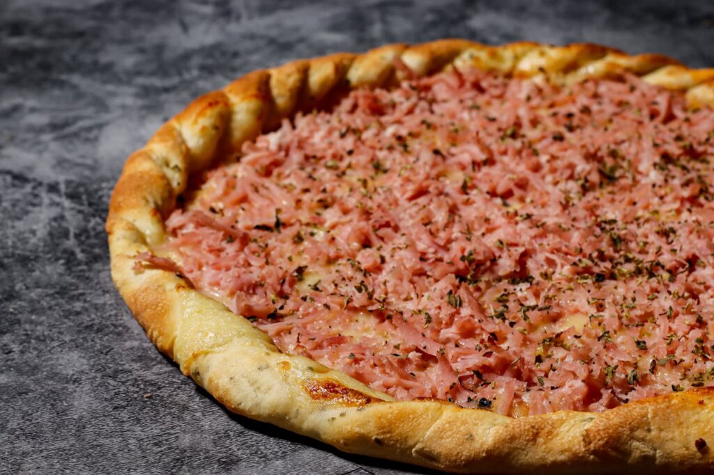 Close-up of a savory ham pizza on a marble surface in Rio de Janeiro, Brazil.